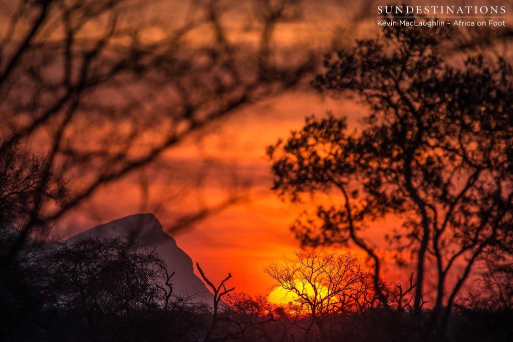 A peak of the Drakensberg Mountains peeks over the horizon as the setting sun bathes the sky in bright colours of summer
