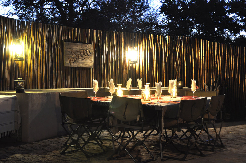 The dinner table at nDzuti Safari Camp. Under the stars and next to a crackling fire. Photo by Kevin MacLaughlin.