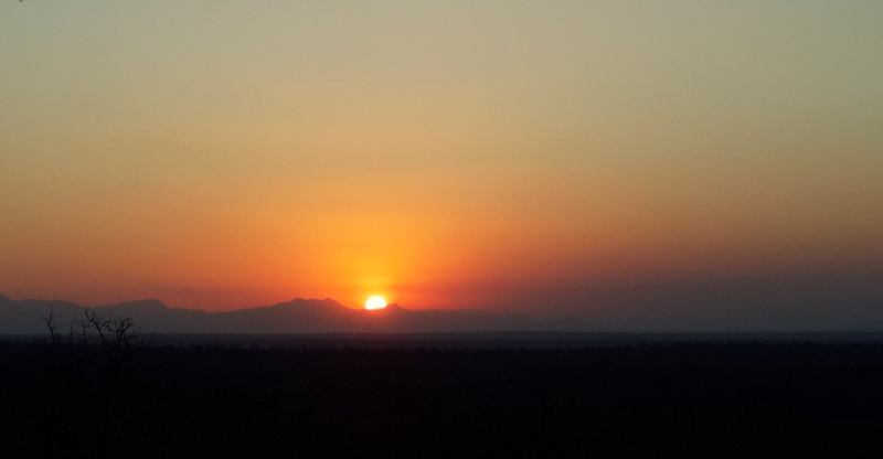 The view from the game-viewing tower in the evening: the sun setting behind the Drakensberg Mountains.