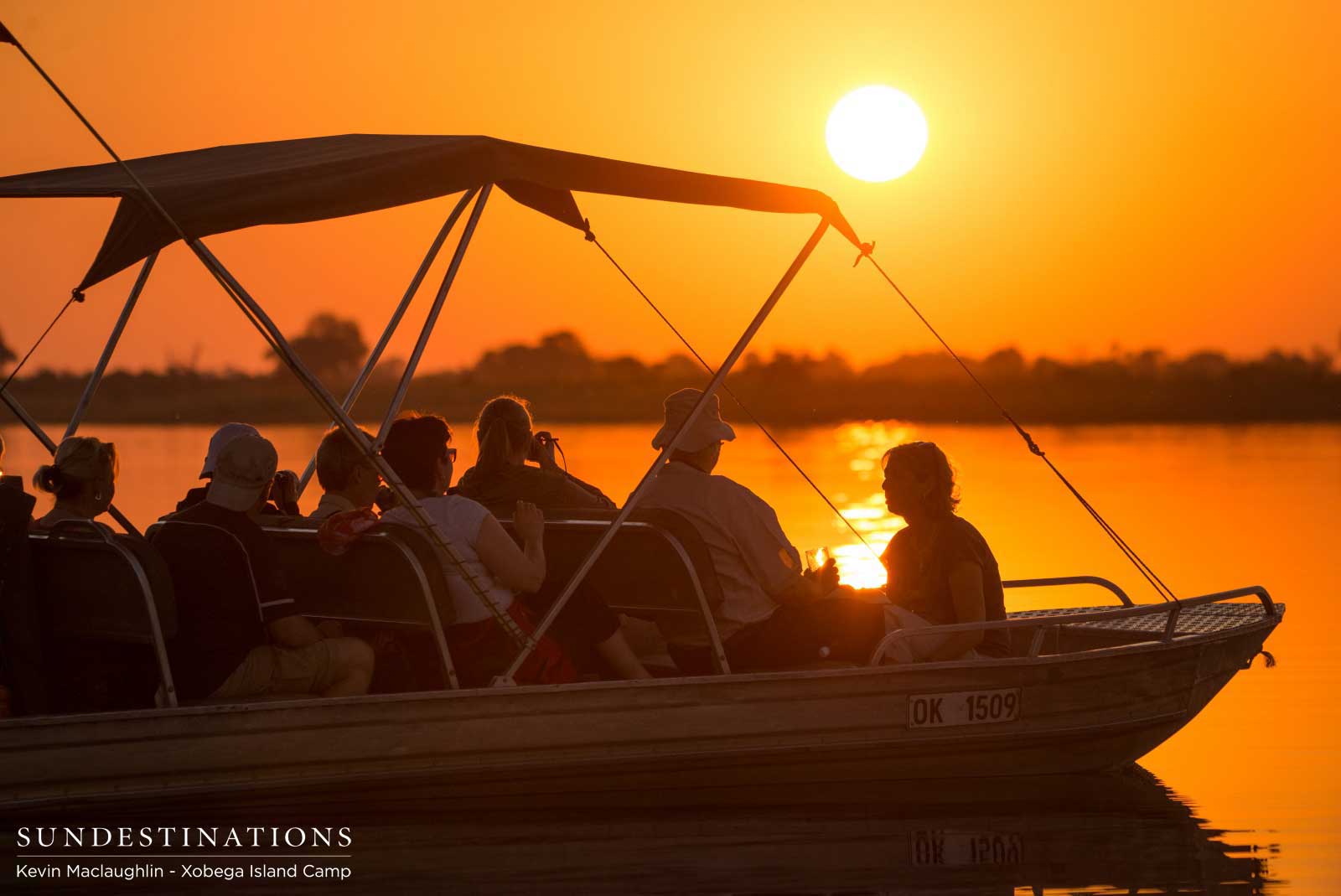 Xobega Island guests admire the sunset from their boat in the Okavango Delta