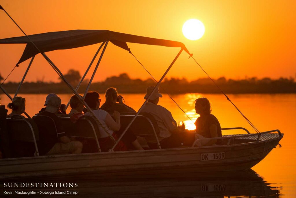 Xobega Island guests admire the sunset from their boat in the Okavango Delta Xobega Island guests admire the sunset from their boat in the Okavango Delta